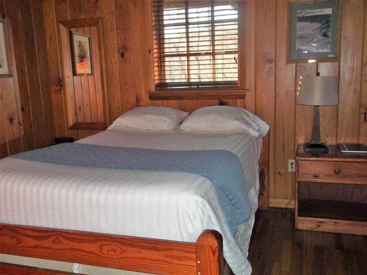 View of the bedroom at Cabin 6 including bed, side table and exterior window